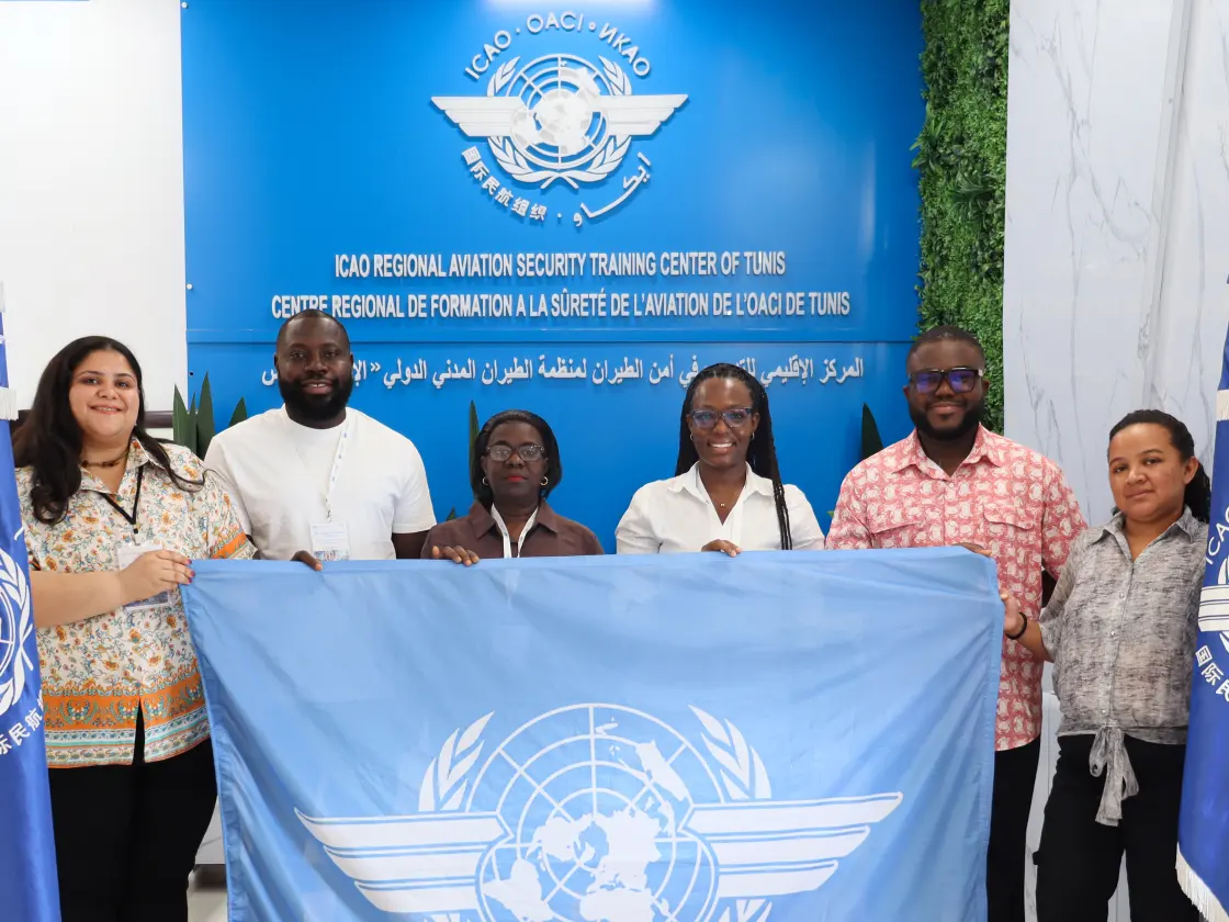 Stagiaires déployant le drapeau de l’OACI à l’issue d’un cours pour inspecteurs de la sûreté de l’aviation